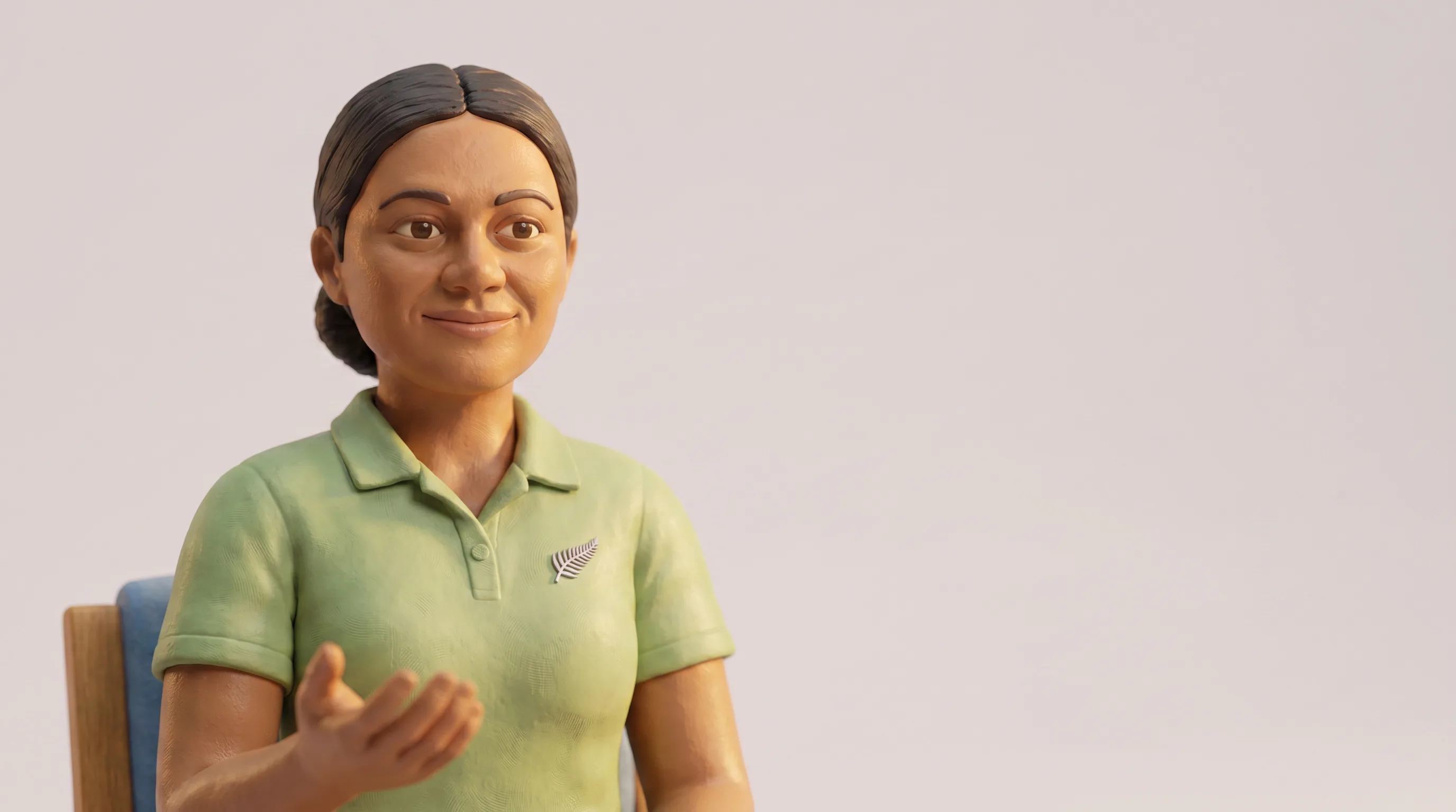 A claymation nurse in a green polo shirt with a silver fern pin, seated and turned slightly towards camera, one hand open mid-gesture, as if mid-sentence. Sculpted clay texture shows on her face and sleeves. She sits to the left of frame against a plain warm-grey background.